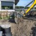 Using an excavator to bury a 10 m3 concrete septic tank located in the garden next to the house