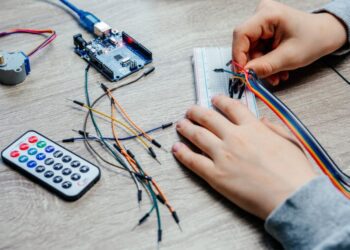 A child plugging cables to sensor chips while learning arduino coding and robotics