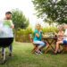 Multiracial couple cooking food on grill for friends Outdoor garden barbecue party Friends laughing and having fun