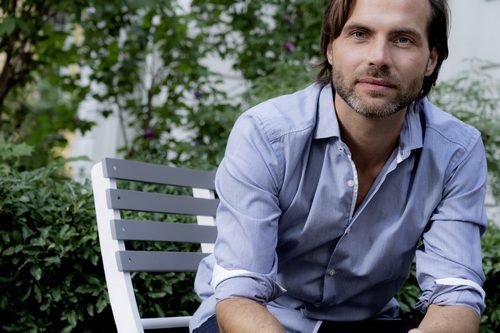 Portrait of confident man sitting on chair in garden