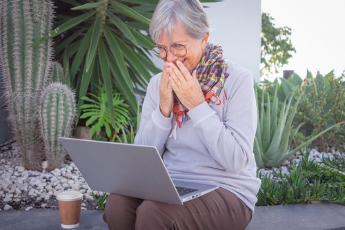 Happy mature senior woman laughing in video chat using laptop co