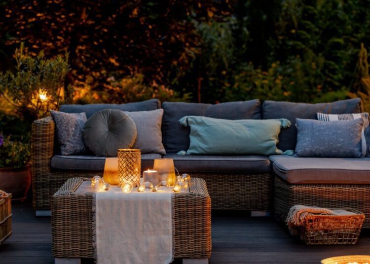 Warm summer night in the garden with trendy furniture lights lanterns and candles