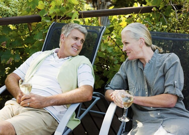 Couple sitting on garden chairs with wine