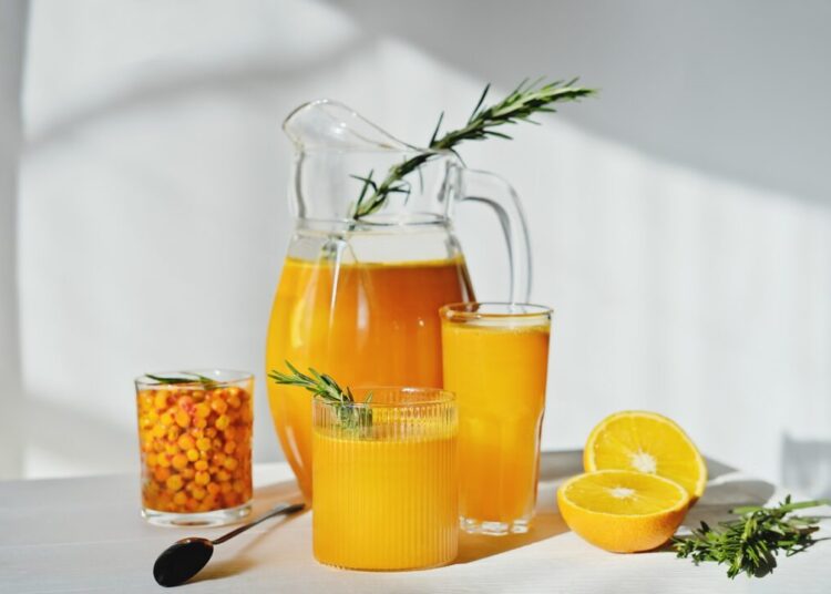 raw sea buckthorn and orange juice in glasses with rosemary antioxidant drinkfor immunity boost in spring vitamin juice for healthy life