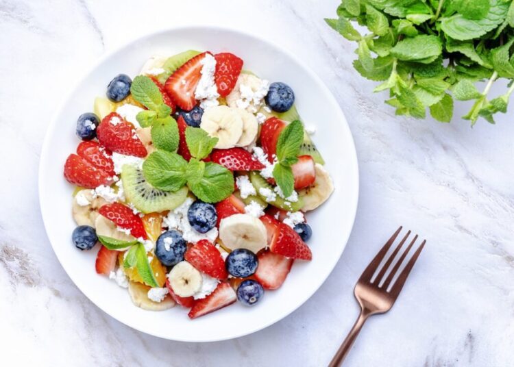 Summer fruit and berry salad with cottage cheese and mint leaves