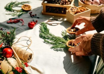 Woman making Christmas arrangement with fir branches and dried oranges Female hands creating Christmas craft handmade decor New year celebration Winter holidays